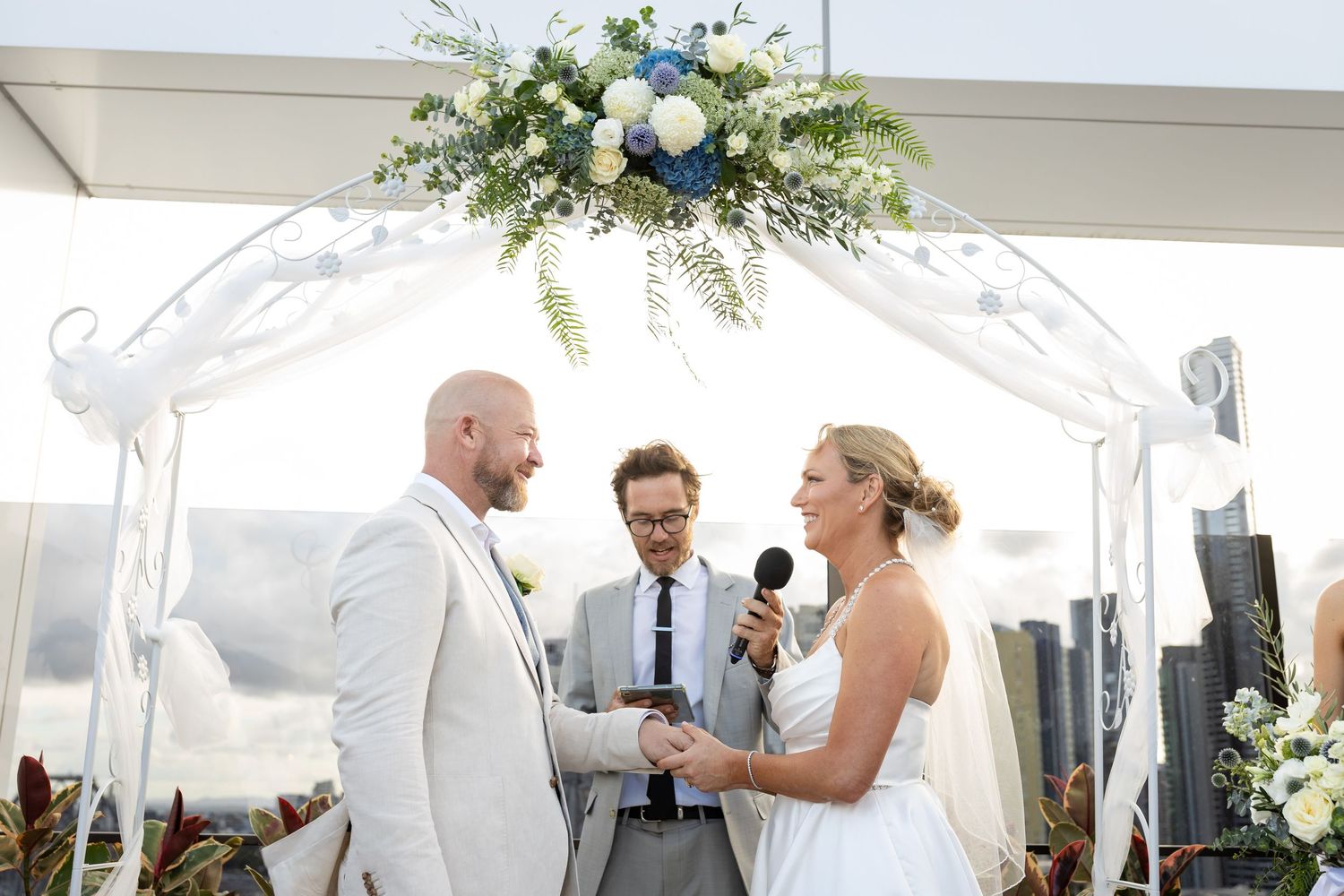 White wedding ceremony setup with floral arrangements and decorative arch on a rooftop venue.wedding ceremony at iris rooftop hotel in brisb