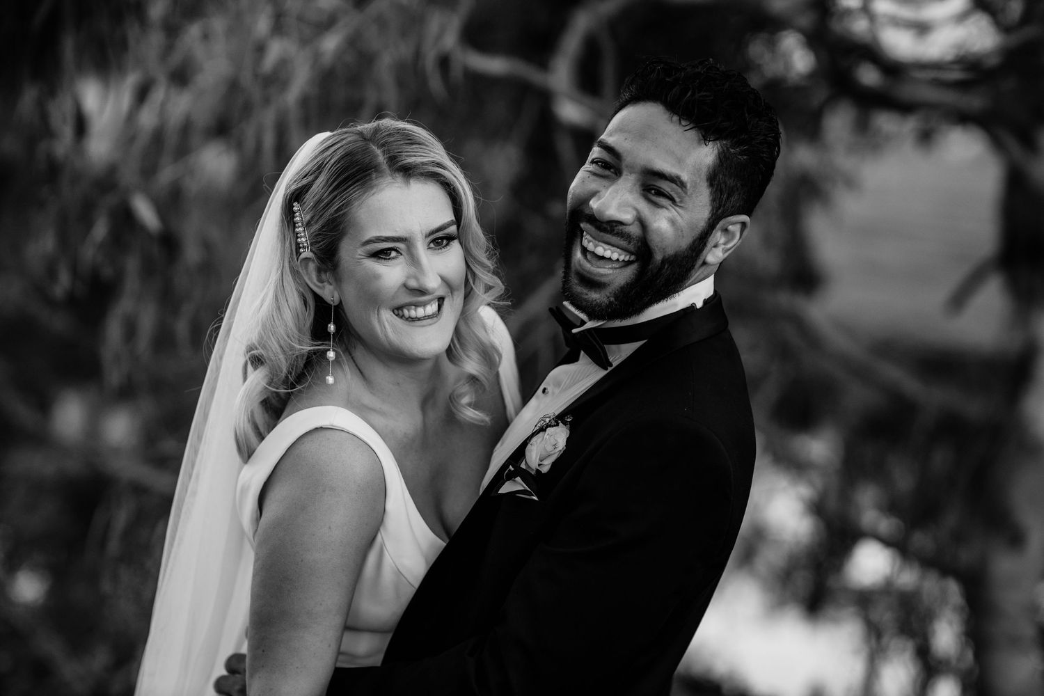 Wedding couple laughs together during black and white outdoor portrait session.