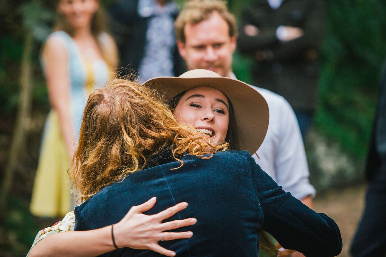 People sharing warm embraces during outdoor gathering.