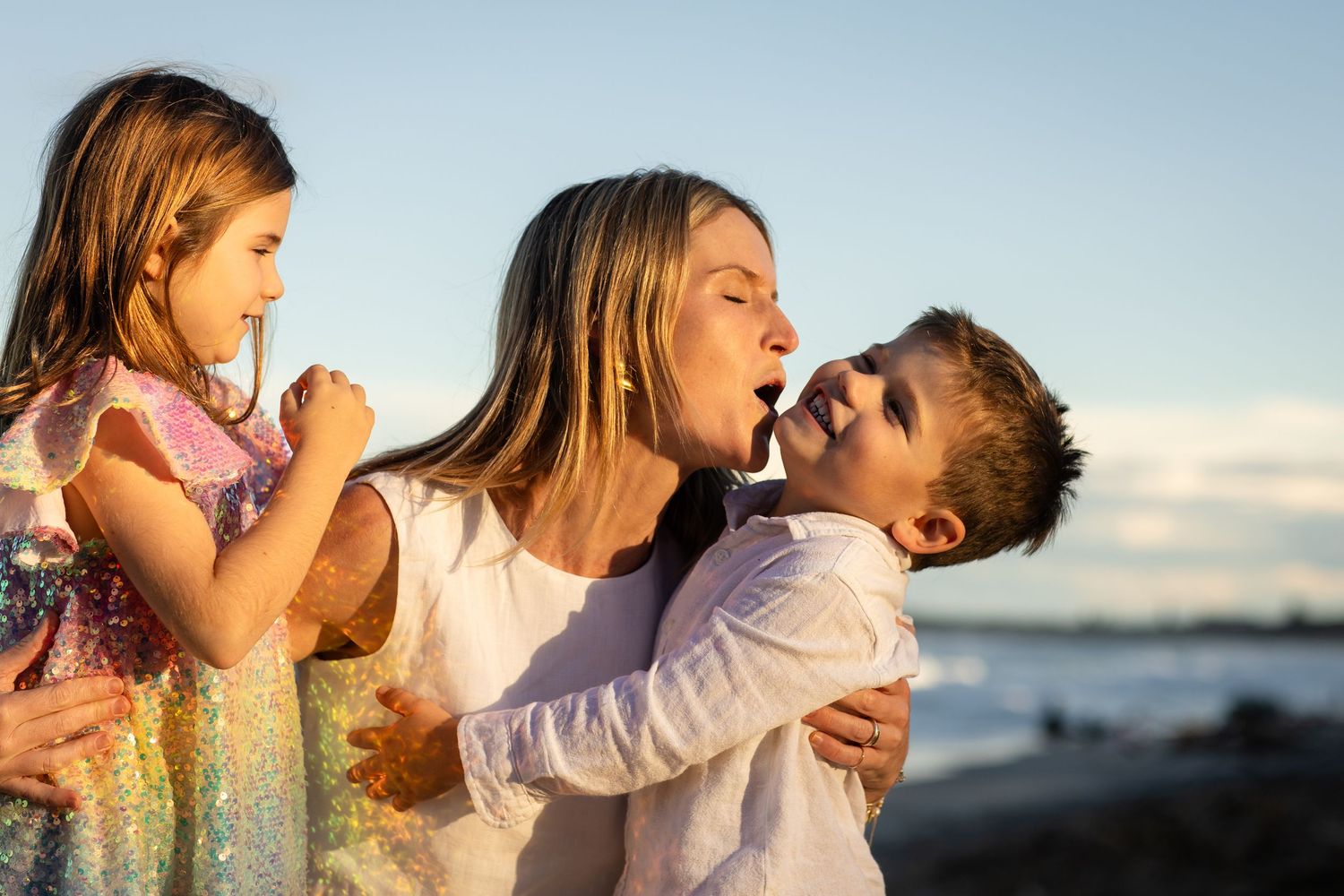 Playful family members sharing affectionate moments by the ocean at sunset.Family photography cabarita New South Wales