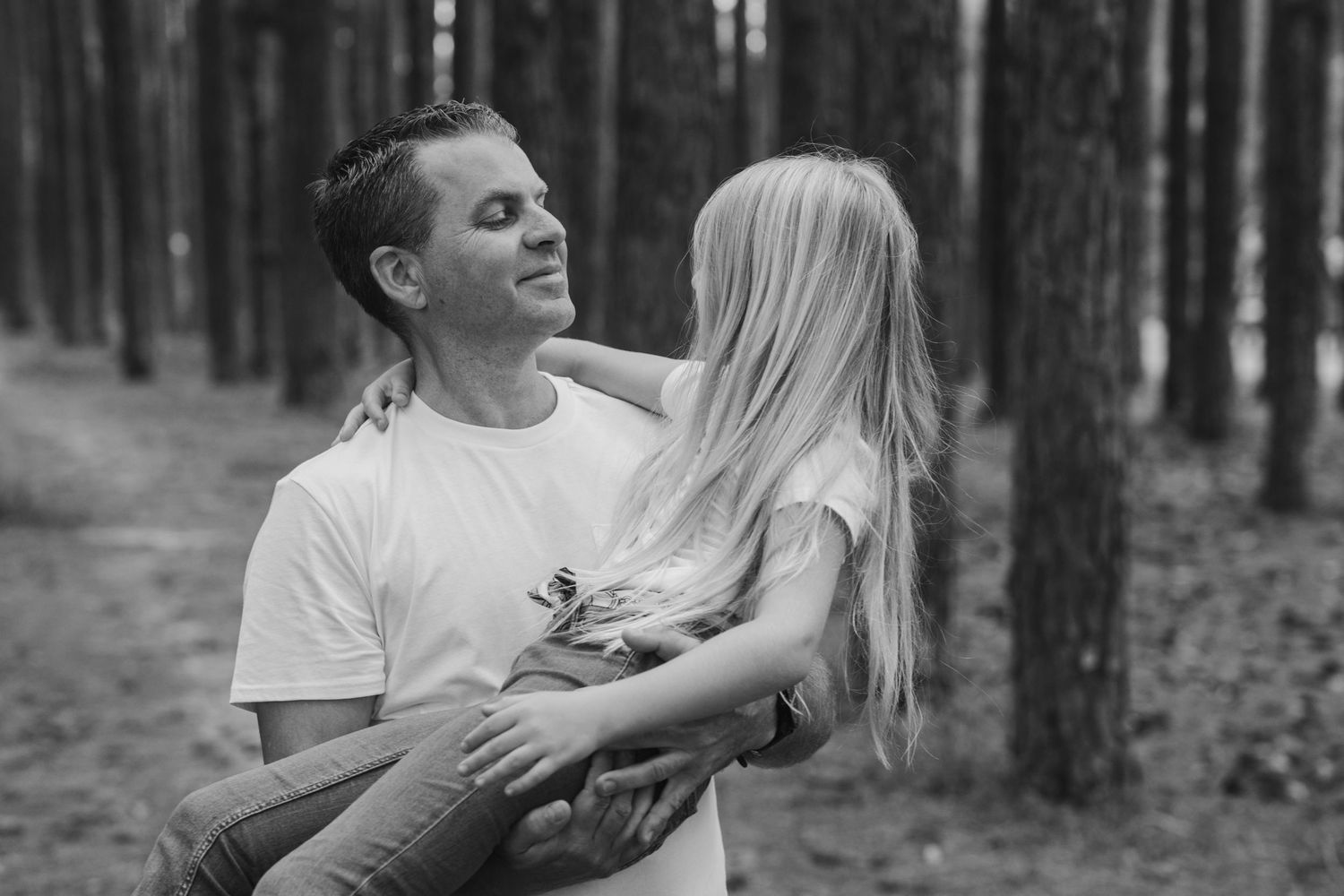 Playful interaction between two people among tall pine trees in a forest.Pizzey park family photos. Gold Coast