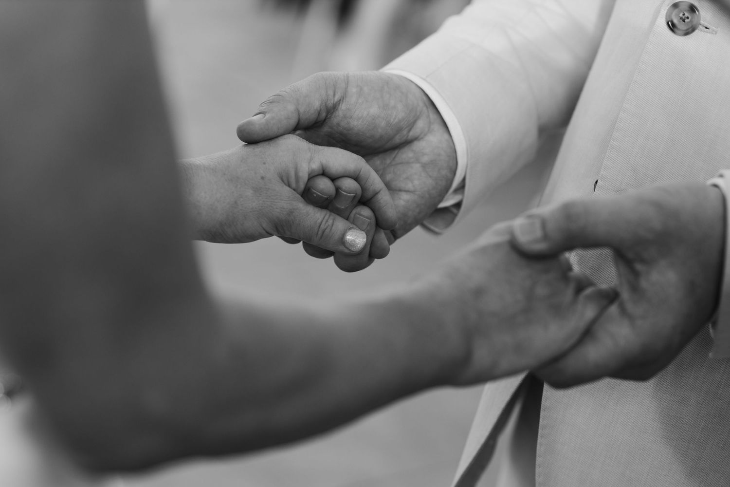 Close-up black and white shot of hands exchanging rings during wedding ceremony.