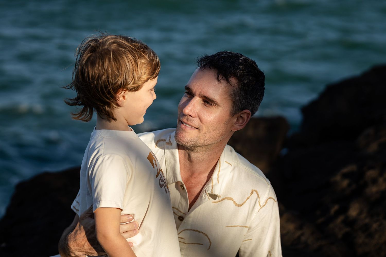 Intimate seaside moment against deep blue ocean background.Gold Coast candid family photographer.