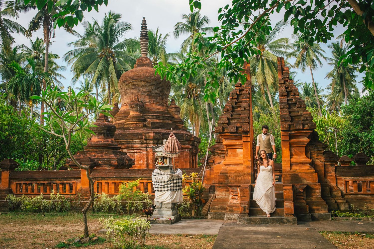 Ancient Buddhist temples and palm trees in tropical landscape panorama. Bali destination wedding.