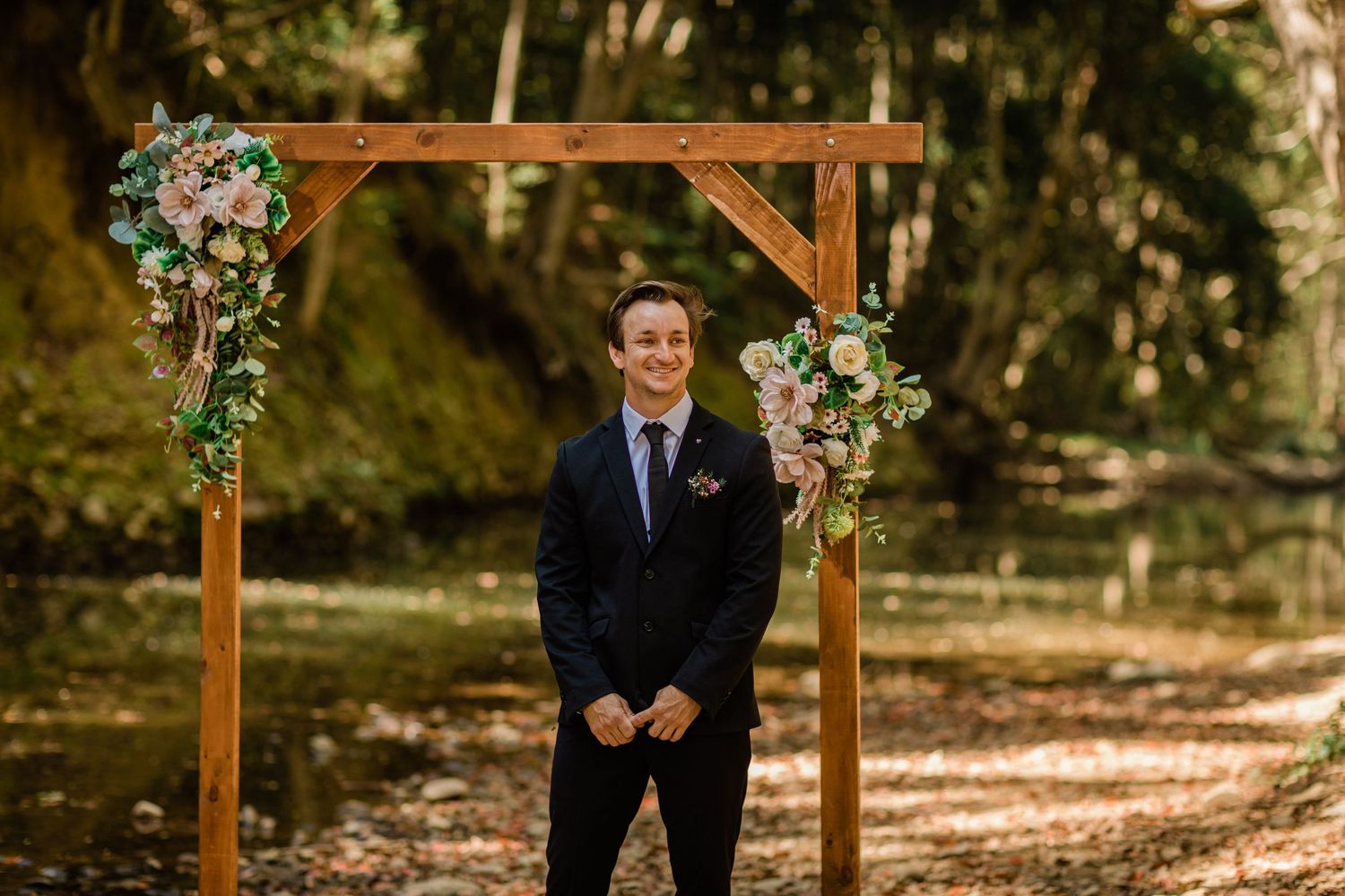 Outdoor wedding ceremony setup with wooden arch decorated with floral arrangements.Currumbin Valley wedding photography Gold Coast