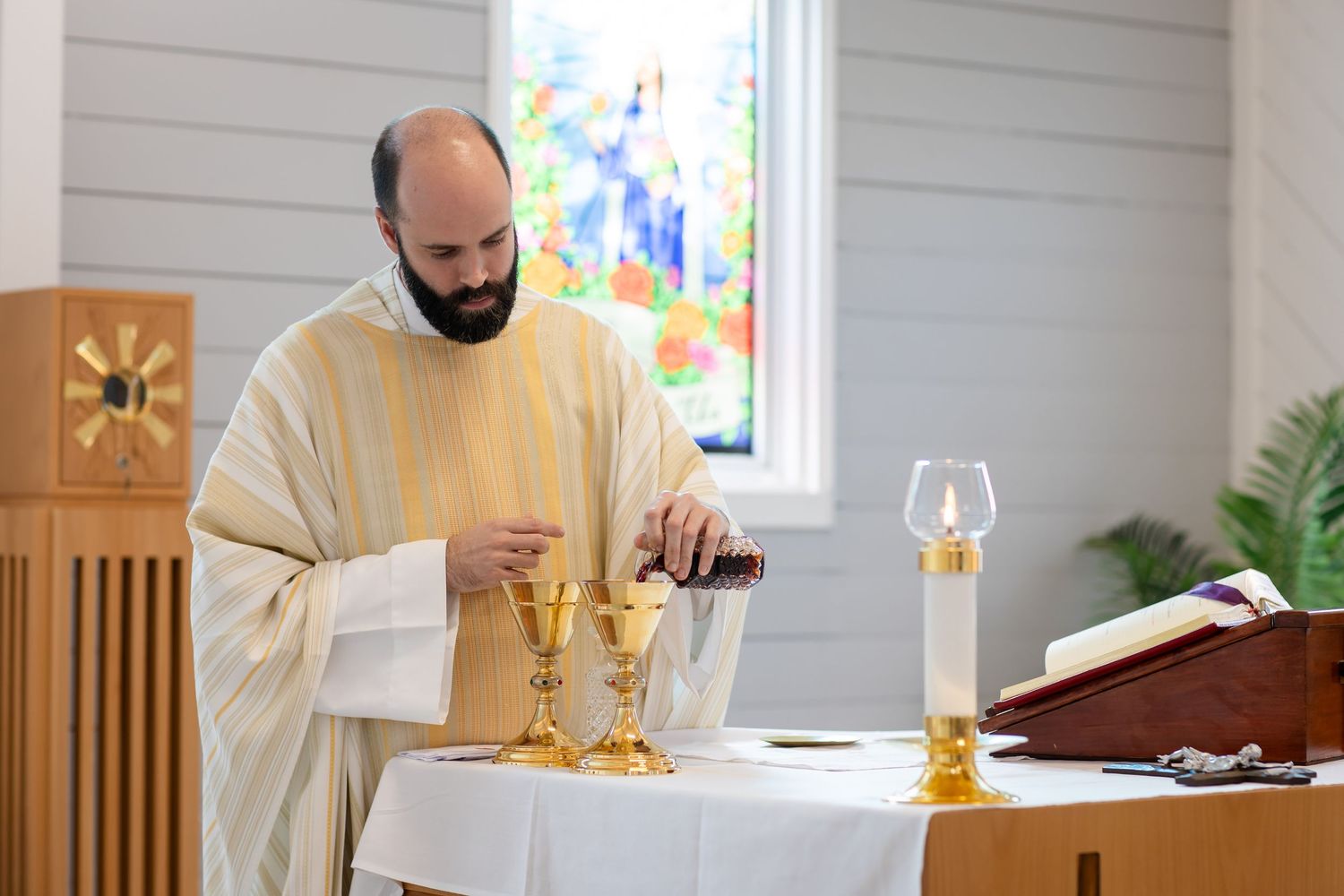 Wedding ceremony in a bright white chapel with wooden accents and stained glass windows.