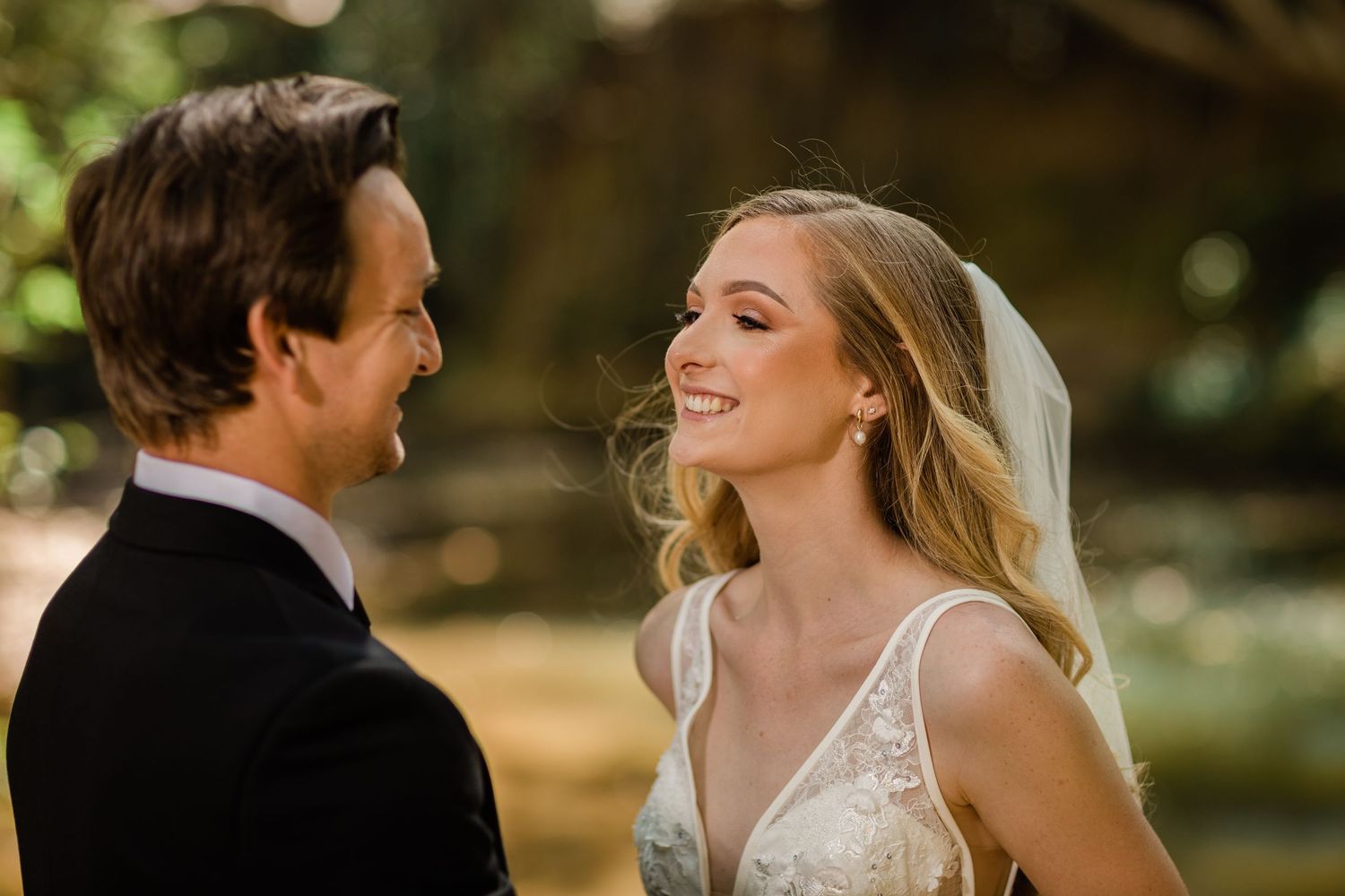 Bride in lace dress and groom share romantic moments during outdoor wedding portraits.Currumbin Valley wedding photography Gold Coast