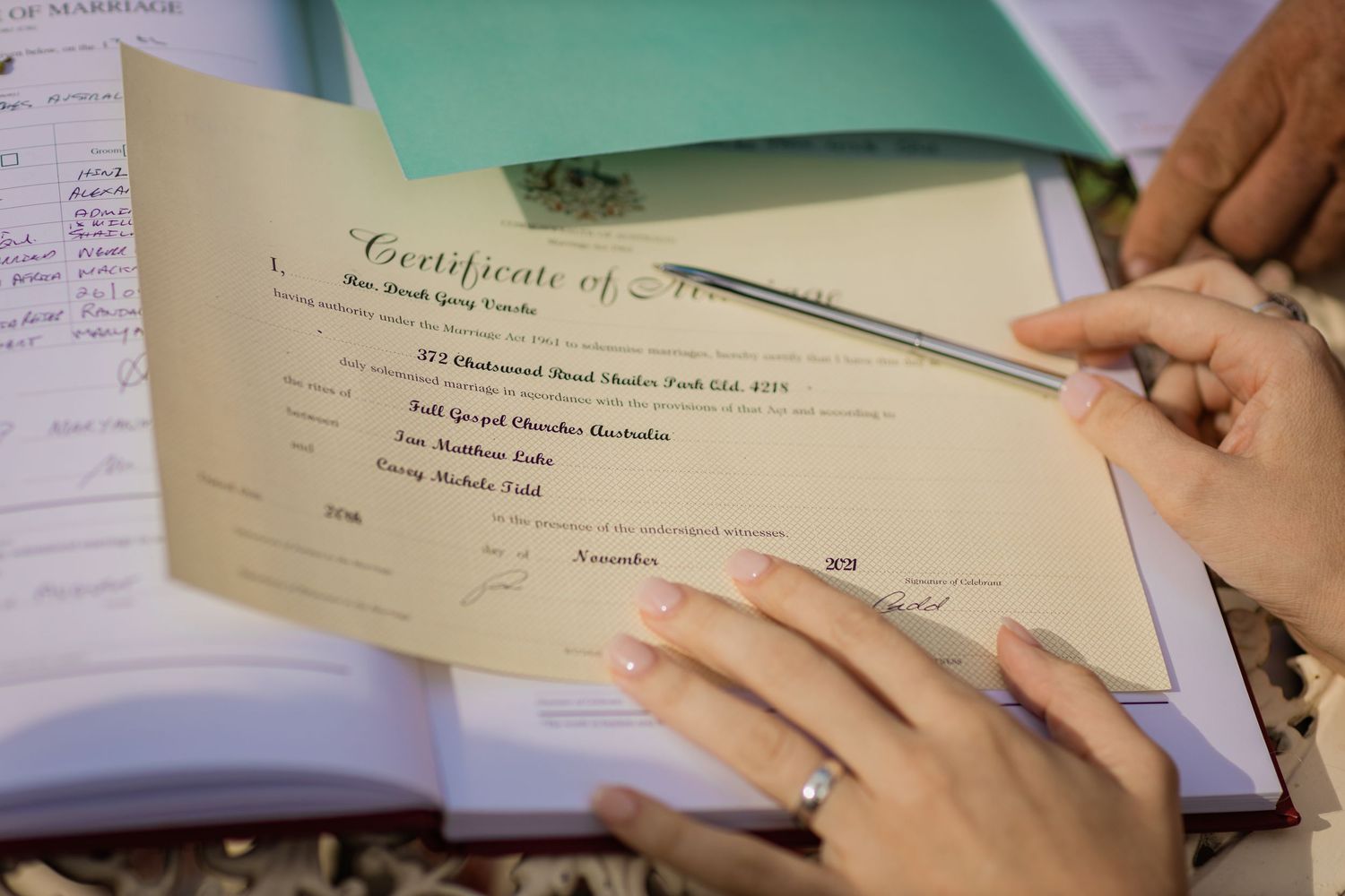 Close-up of hands signing an official certificate document.Gold Coast elopement photographer