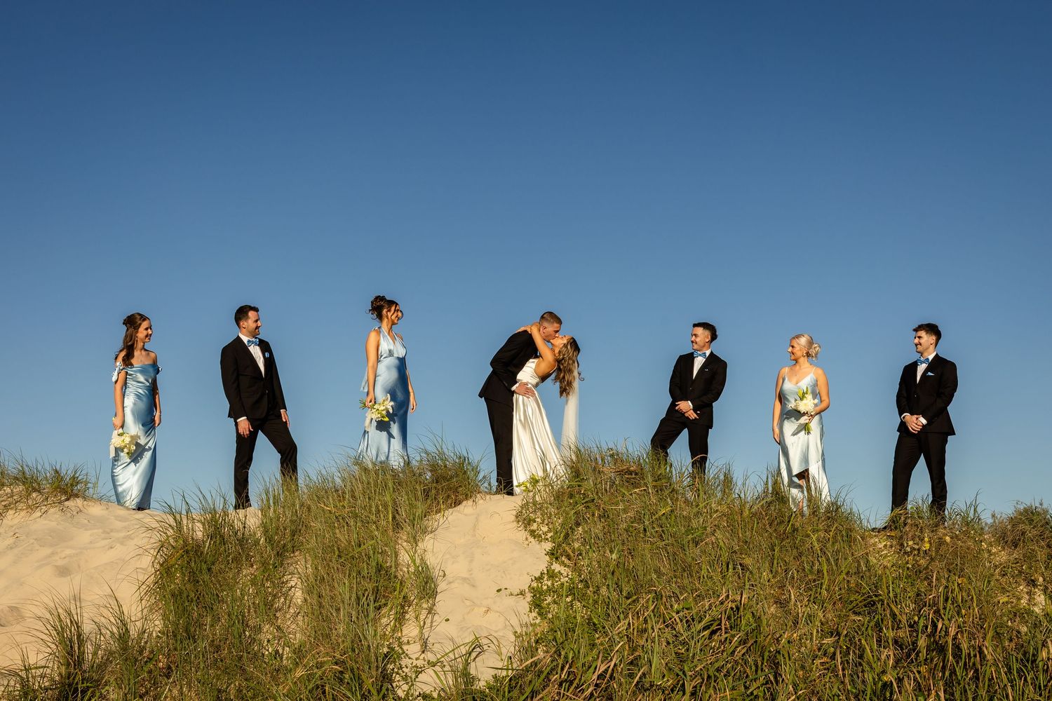 Wedding party stands in line on a scenic coastal dune with ocean views.beach wedding currumbin surf club wedding