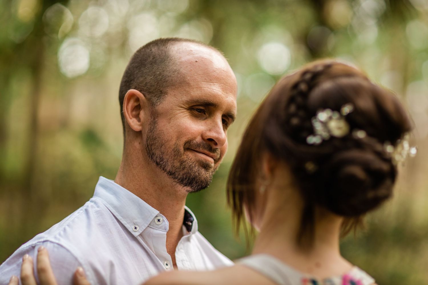 A couple shares a tender moment in a sunlit forest with bokeh effects in the background.Gold Coast elopement photographer