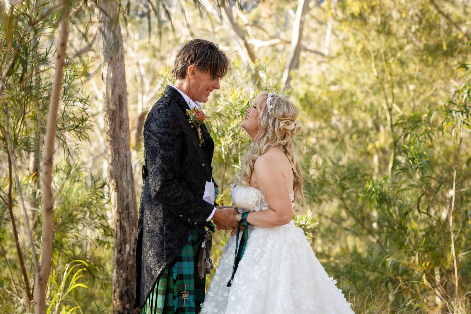 Wedding couple shares intimate moment in Australian bushland with groom wearing traditional Scottish attire.Gold Coast wedding photographer