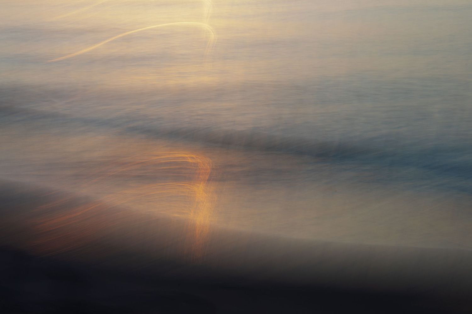 Abstract sunset sky with soft golden light streaking across cloudy horizon.
