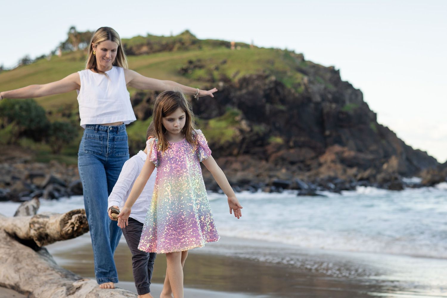 Seaside family photoshoot with green coastal hills and ocean waves in the background.Family photography cabarita New South Wales