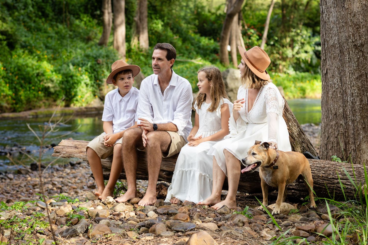 A family with their dog enjoys a relaxing afternoon together in a lush green forest setting.Tallebudgera family photography. Gold Coast