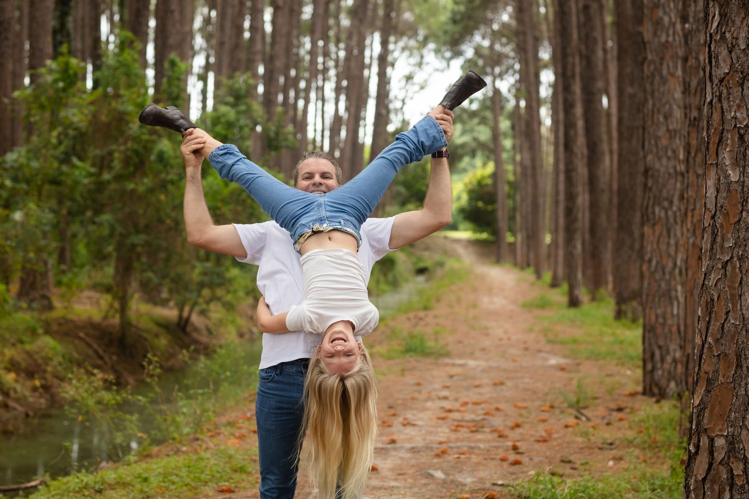 People enjoying a carefree moment on a winding forest trail lined with pine trees.