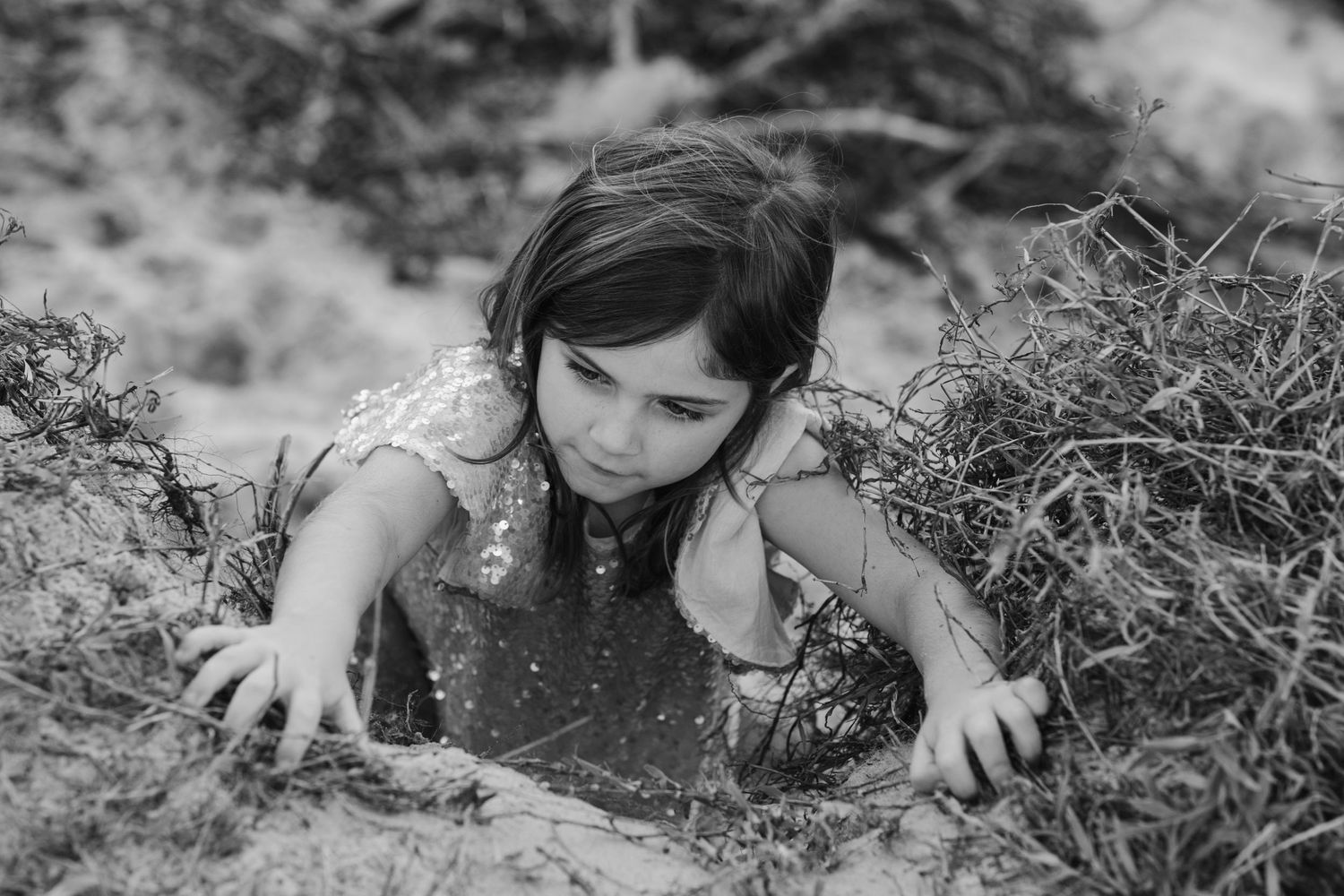 Black and white image of children climbing and exploring outdoors.Gold Coast candid family photographer. Cabarita headland