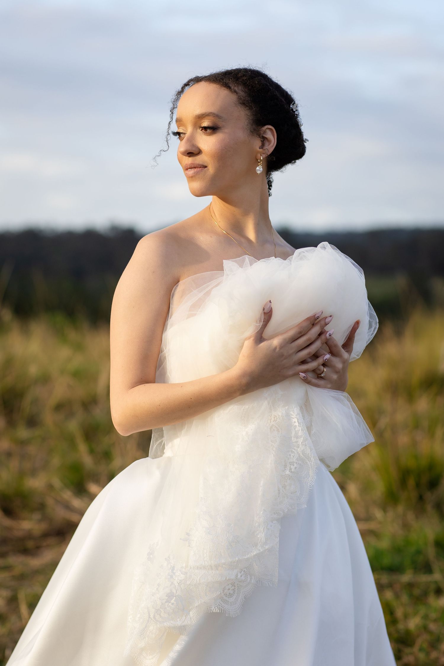 Close-up of bride holding and adjusting her white wedding dress in outdoor setting.The barrow restaurant mount Nathan wedding