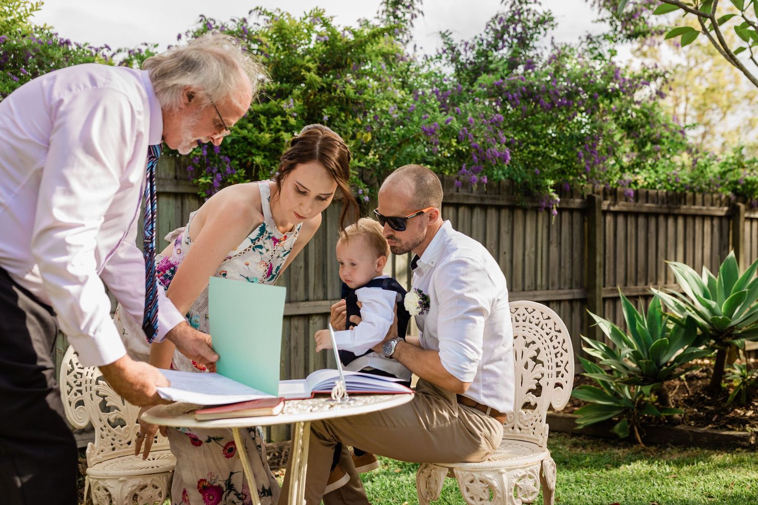 Signing important documents at an outdoor table in a garden setting.Gold Coast elopement photographer