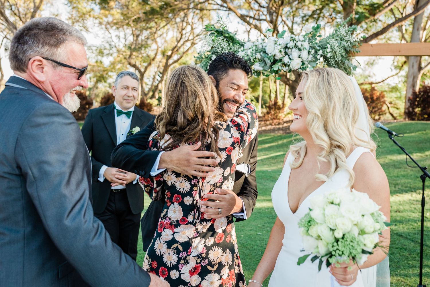 Wedding party gathers on a grassy lawn during golden hour celebrations.