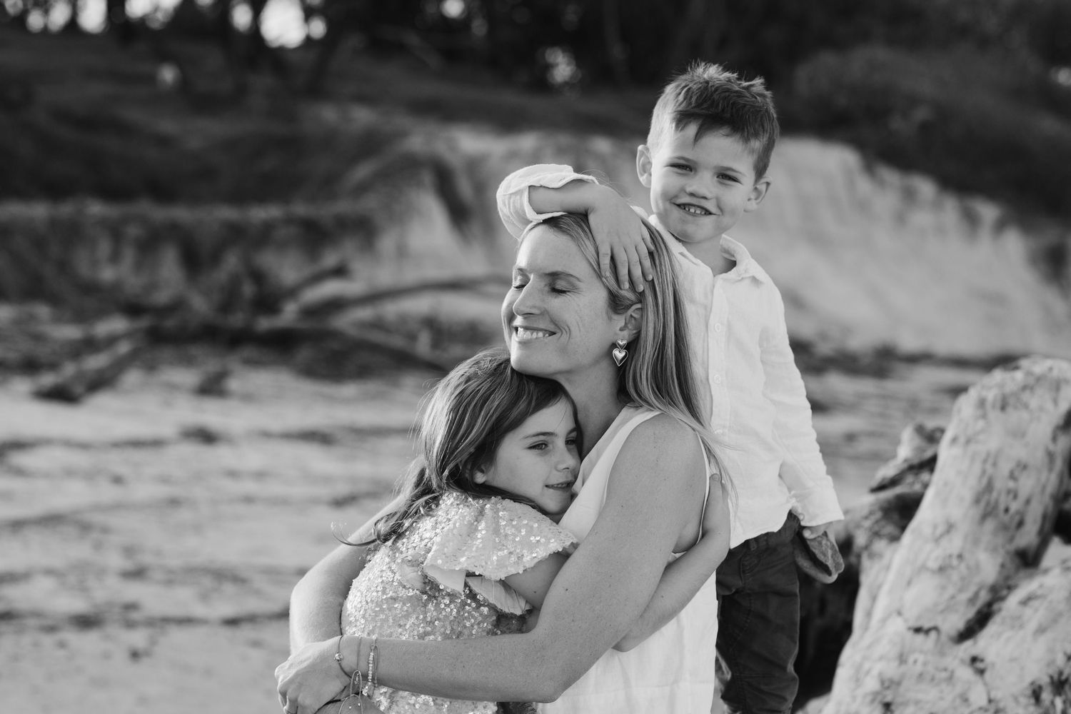 Family enjoying tender moments together on rocky beach during sunset photoshoot. Cabarita headland