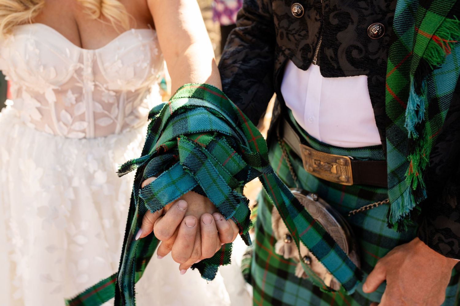 Bridal party in pastel dresses and green plaid attire gather for outdoor mountain ceremony.
