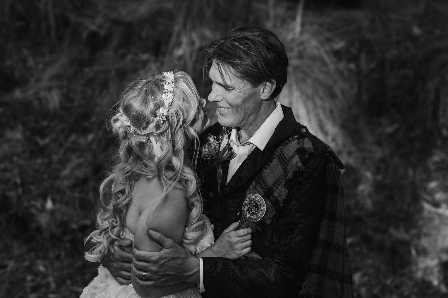 Intimate black and white portrait of couple in Scottish wedding attire against natural backdrop. Gold Coast wedding photographer