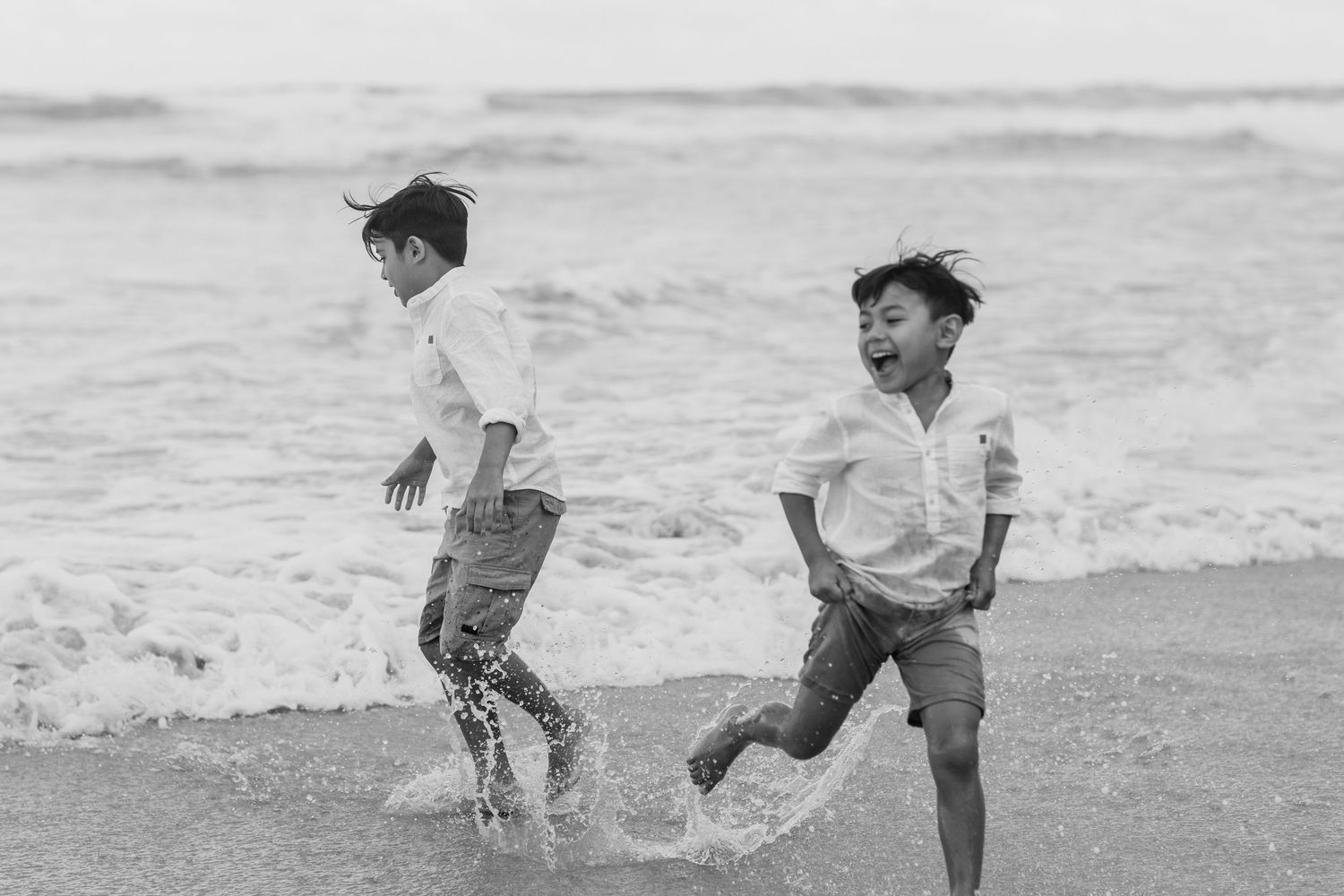 Playful black and white photo of family running on beach.Gold Coast candid family photographer.