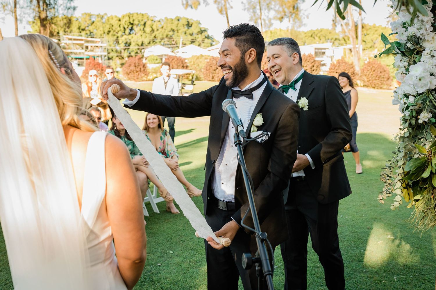 A couple exchanges vows during their wedding ceremony under a floral arch in a garden setting. Surfers Paradise Golf Club wedding.