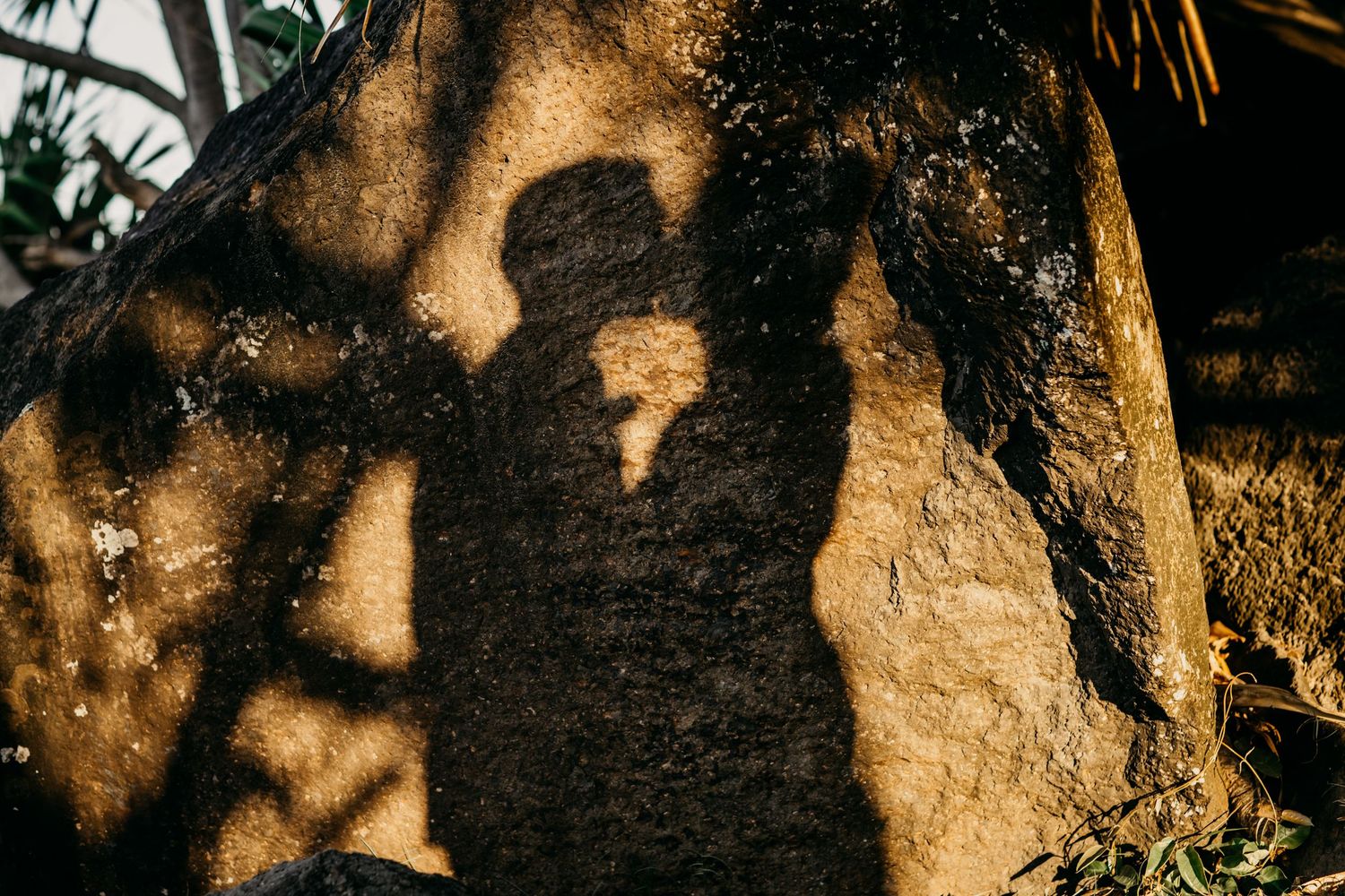 Silhouettes cast romantic shadows on a textured stone wall during sunset.Gold Coast hinterland wedding photographer