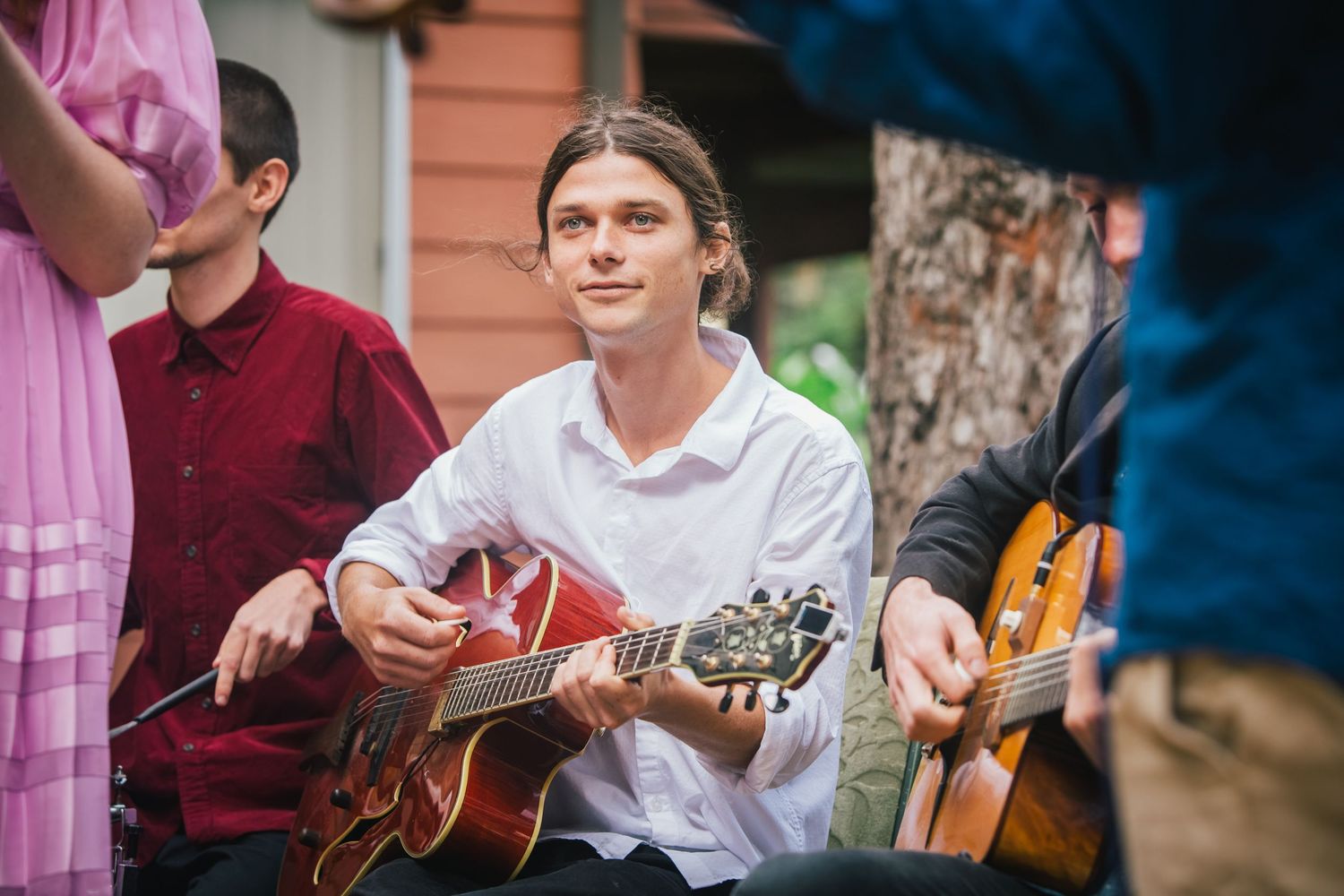 People gathered outdoors playing acoustic guitars in casual setting.