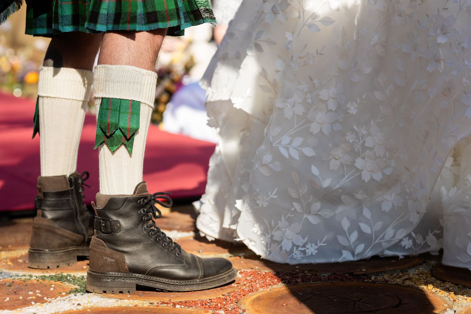 Detail shot of traditional Scottish kilt and formal shoes at wedding ceremony.