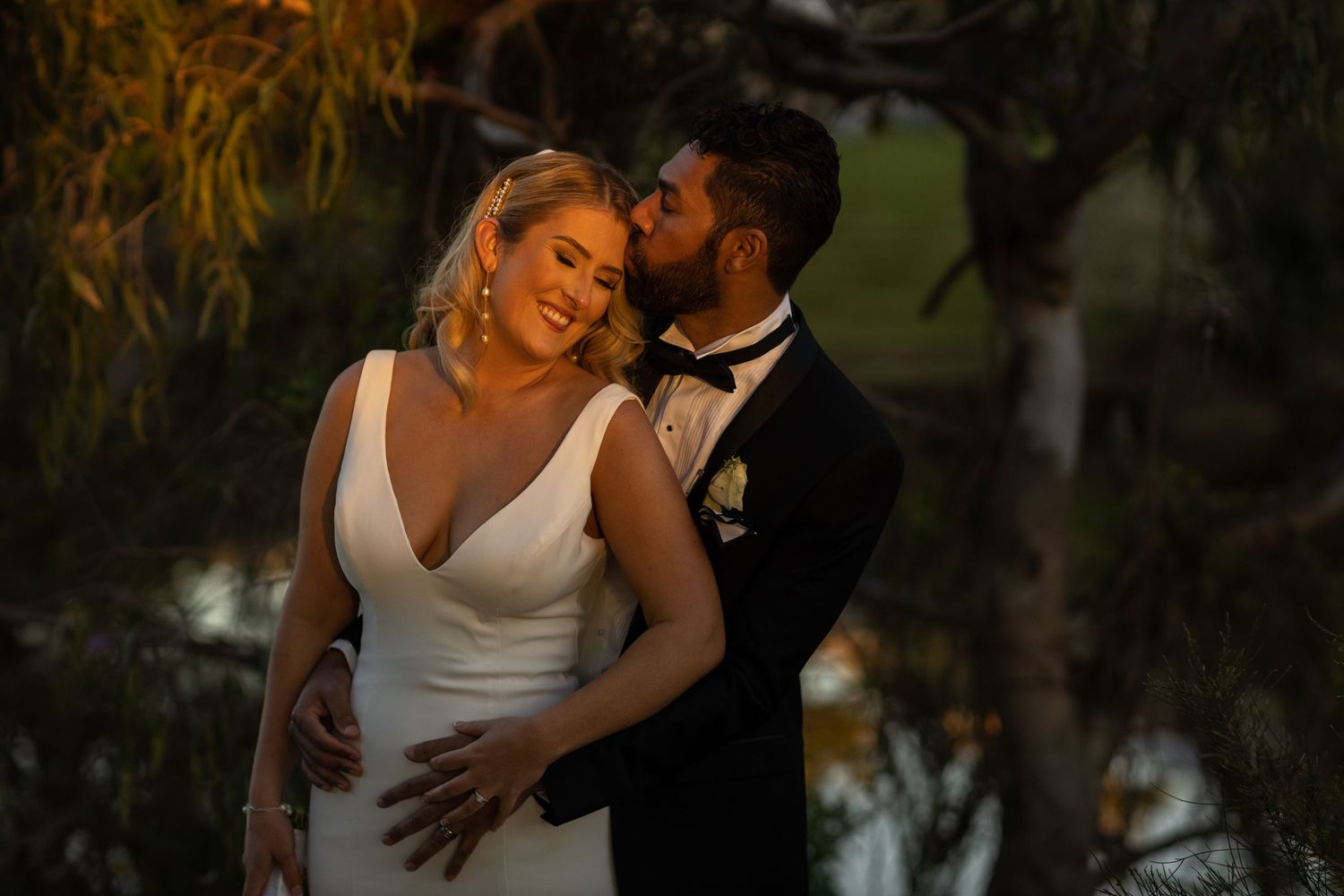 Romantic couple embraces during sunset wedding photo session in a lush garden setting.