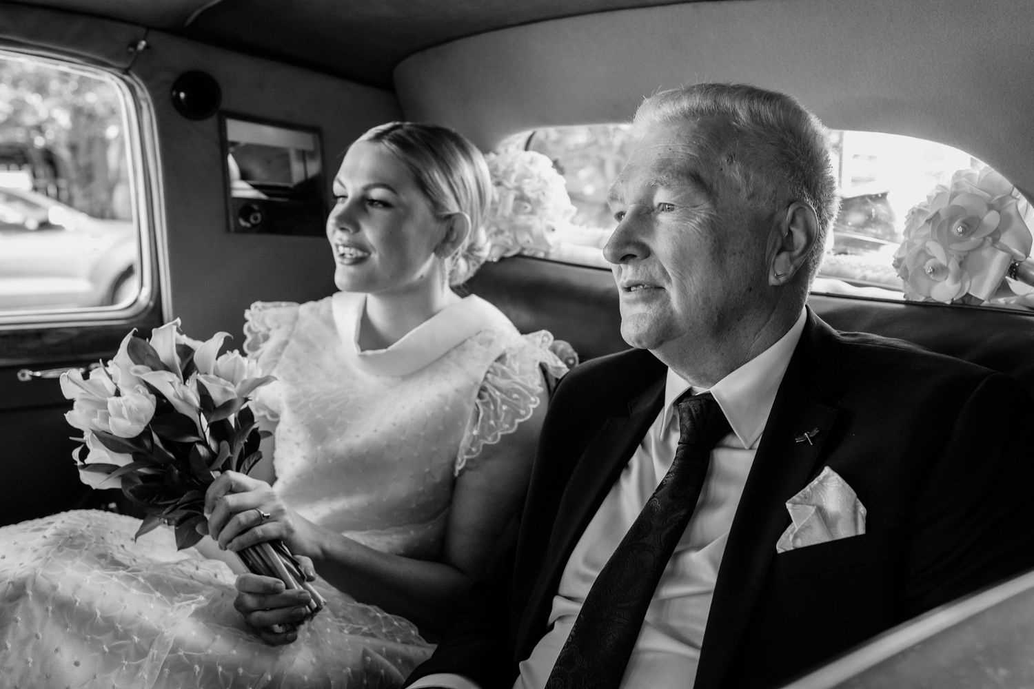 Wedding party members riding together in classic car backseat.