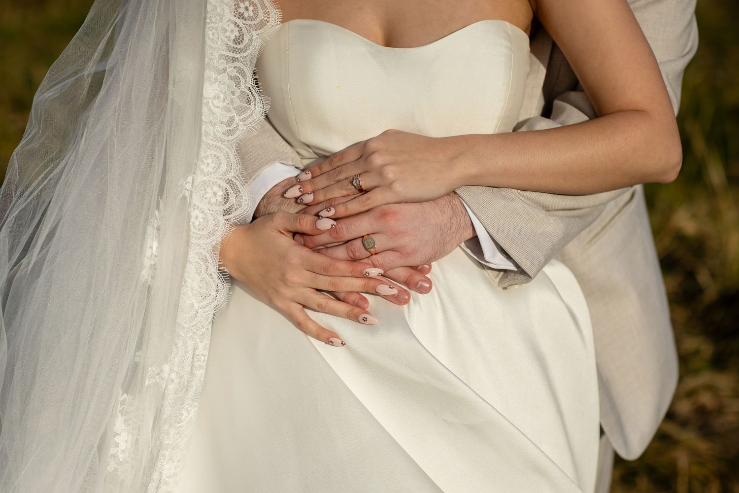 Detail shot of hands with wedding rings against white wedding dress fabric.The barrow restaurant mount Nathan wedding