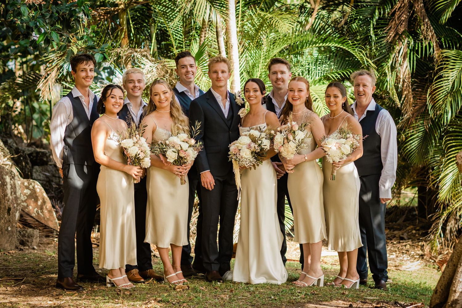Wedding party poses together in a lush tropical garden setting with palm trees and greenery.Miami Burleigh heads beach wedding