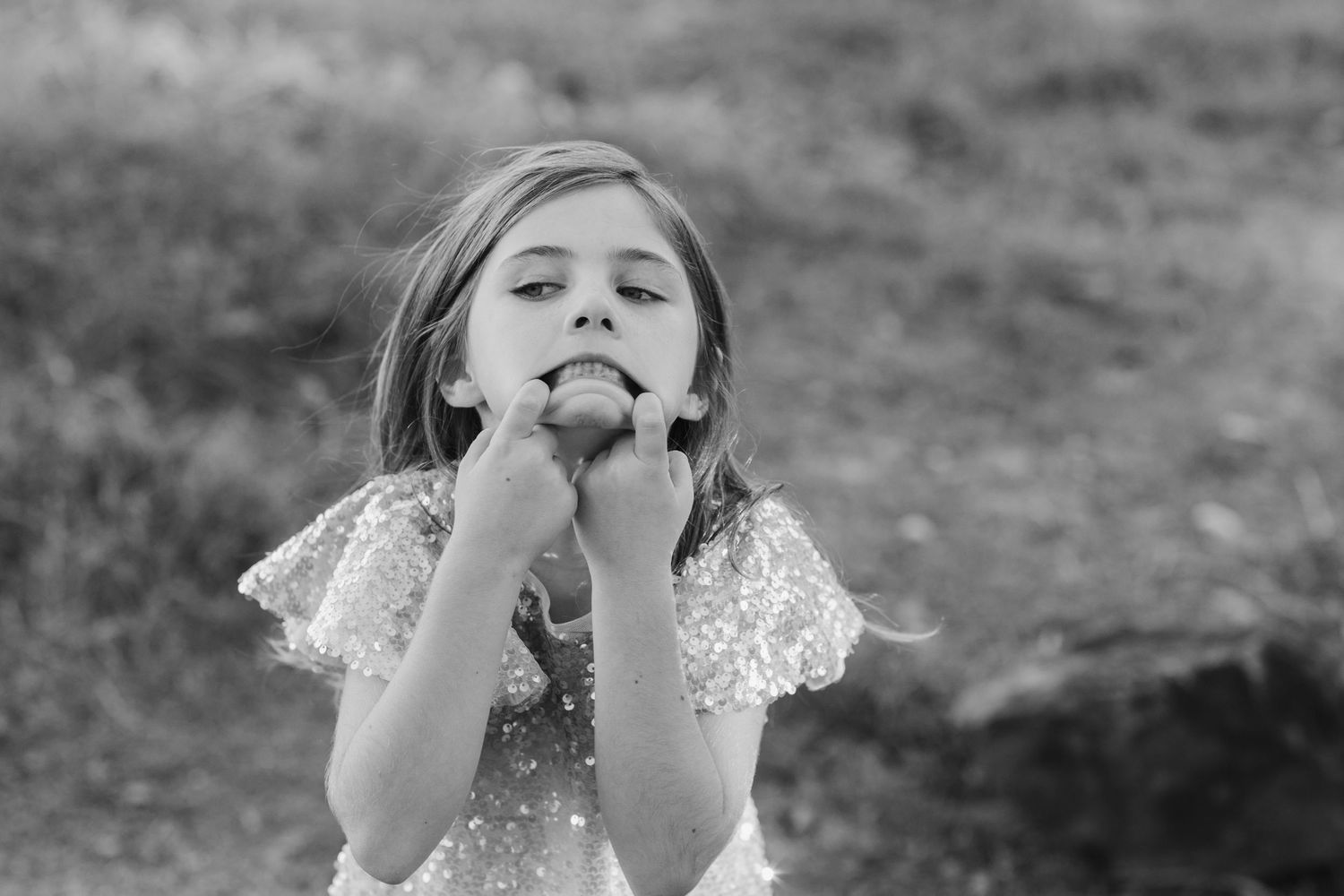 Young person in lace dress makes playful expression in black and white portrait.Cabarita headland