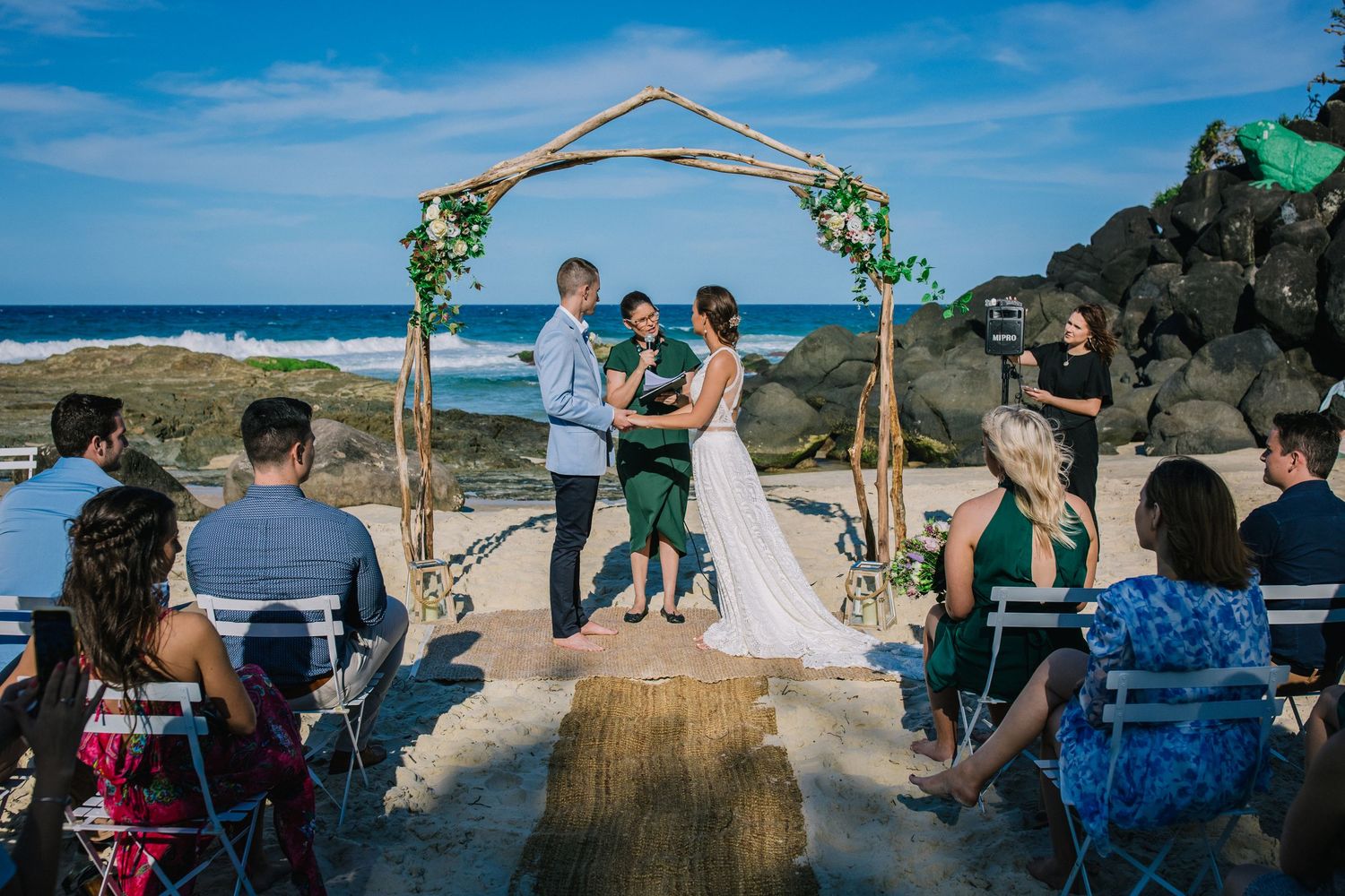 Panoramic view of beach wedding ceremony with wooden arch and seated guests.Gold Coast beach wedding photography. Froggies beach