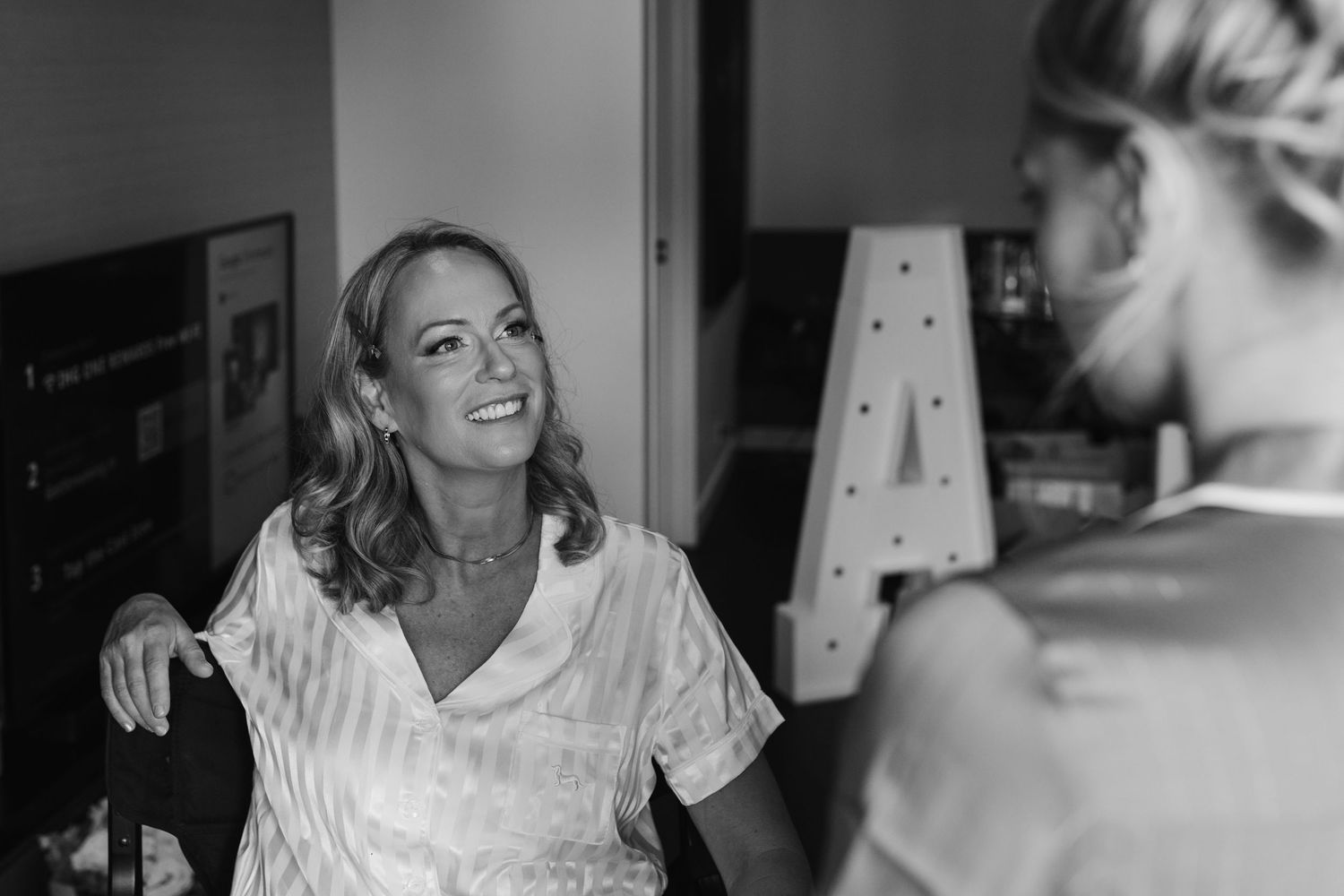 Black and white photo of woman in robe laughing during wedding preparations.