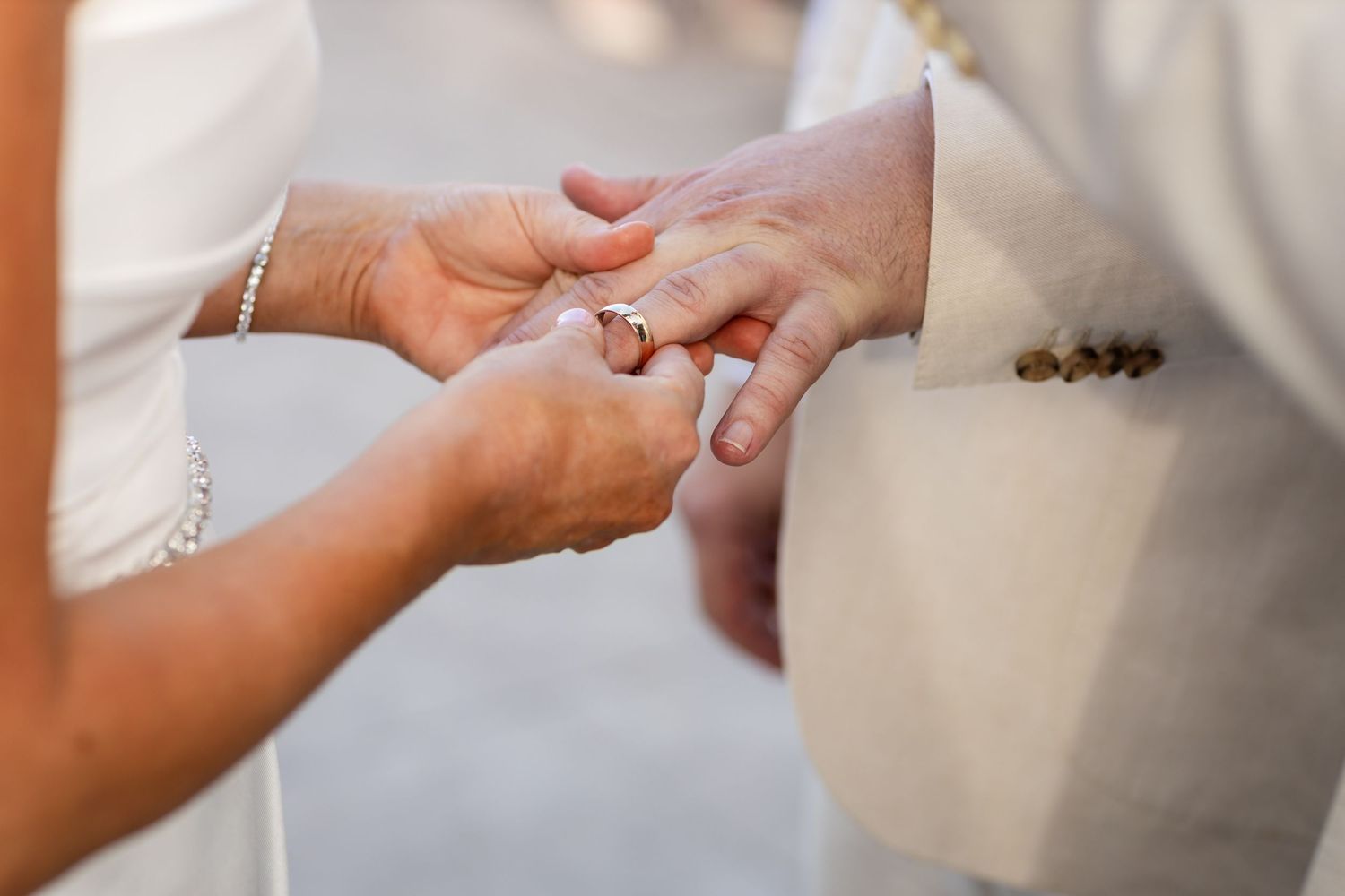 Intimate close-up of hands during a wedding ring exchange ceremony.
