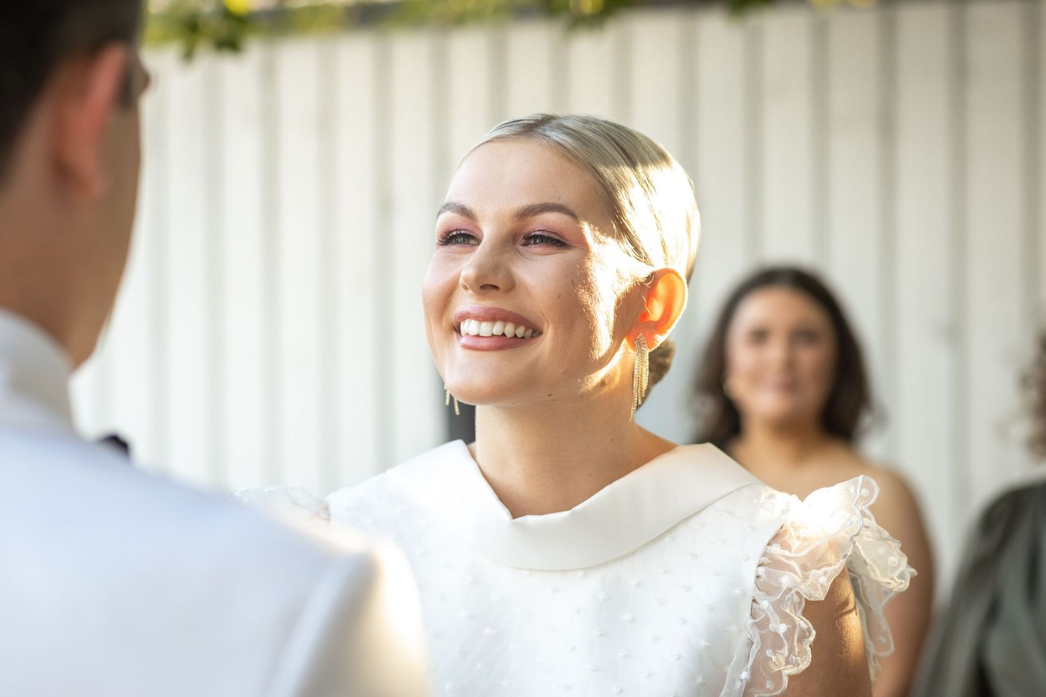 Outdoor wedding ceremony with white decor and natural lighting.