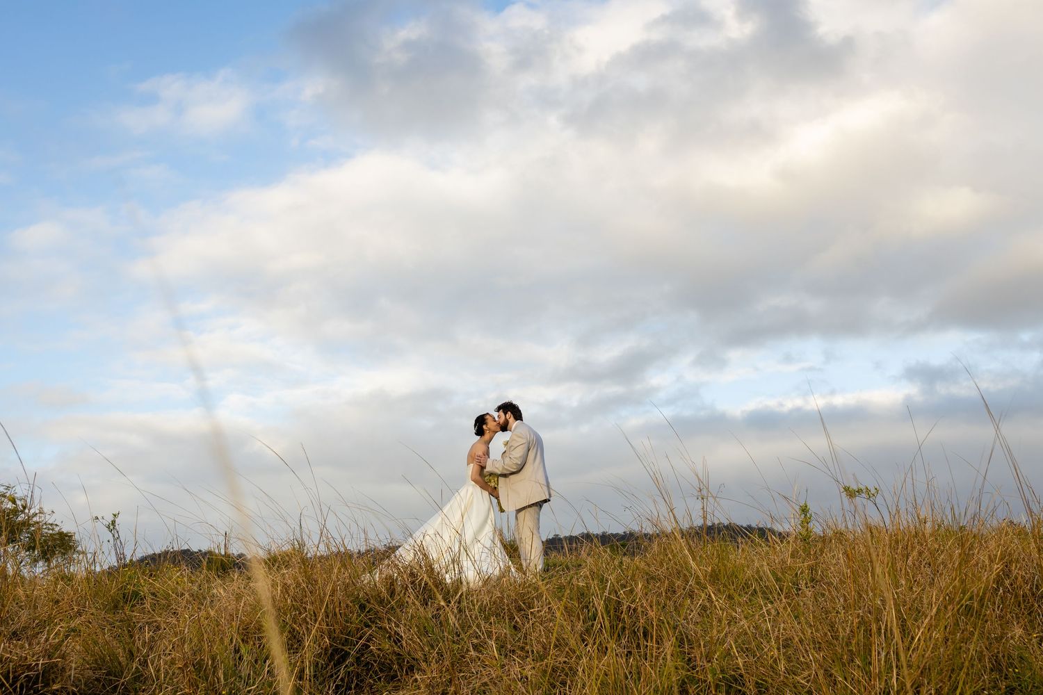 A romantic wedding photoshoot in a scenic field with mountains and cloudy skies in the background.The barrow restaurant mount Nathan wedding