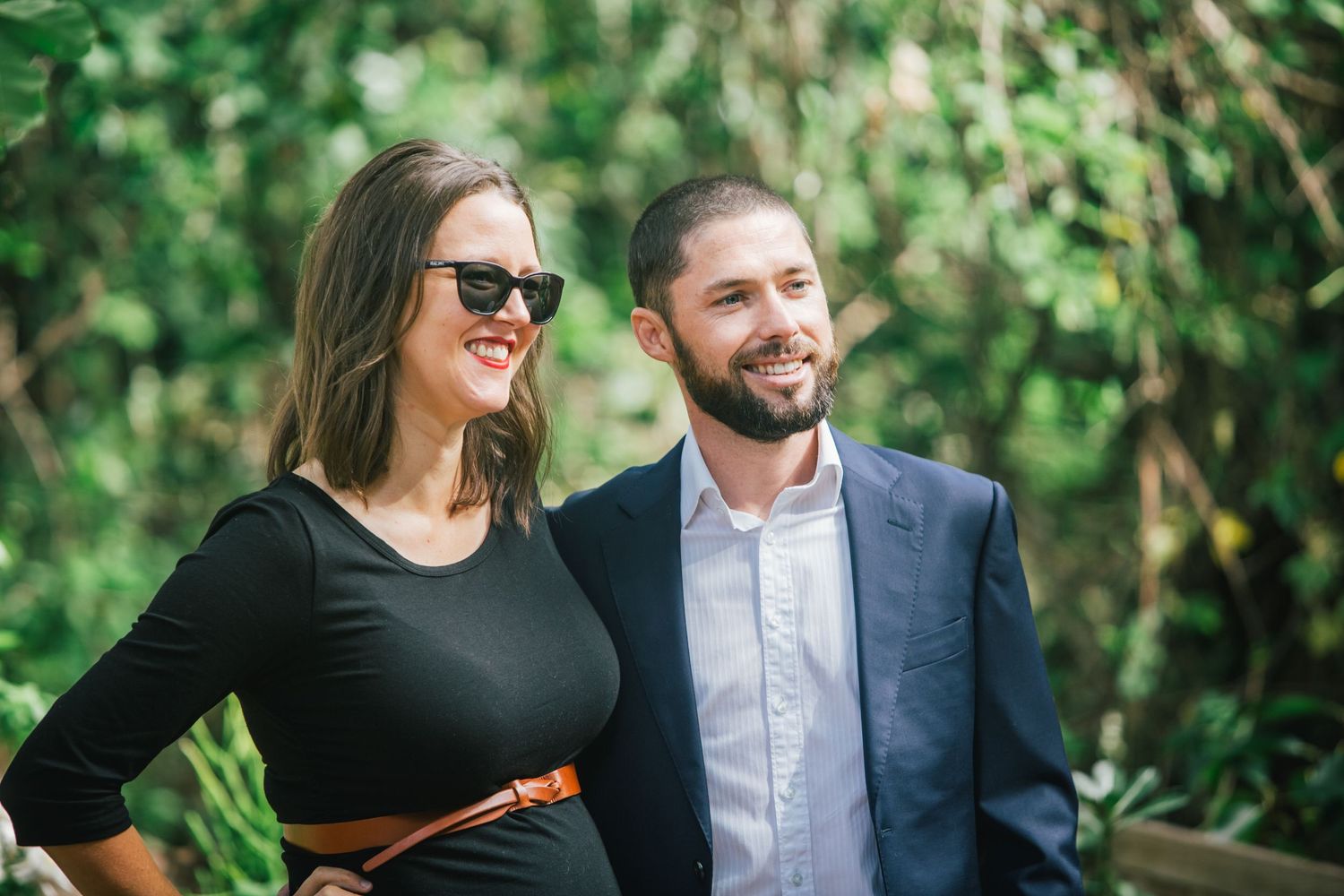 Couple laughing together outdoors surrounded by greenery.