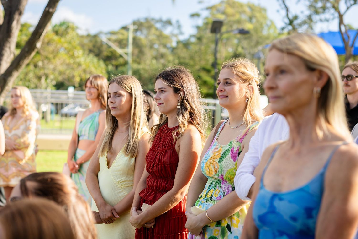 Wedding guests in colorful dresses watching ceremony outdoors on a sunny day.beach wedding currumbin surf club wedding