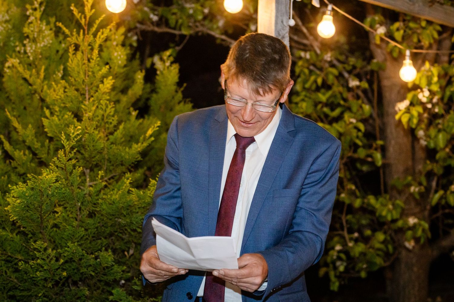 Wedding reception venue decorated with warm string lights and greenery creating a romantic outdoor atmosphere.