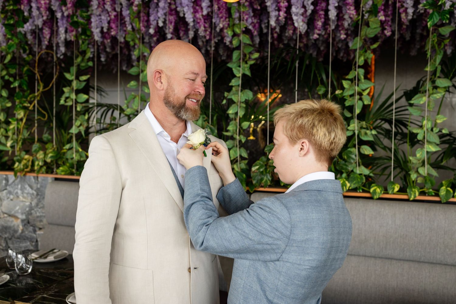 Purple wisteria flowers create a romantic backdrop for wedding photos.