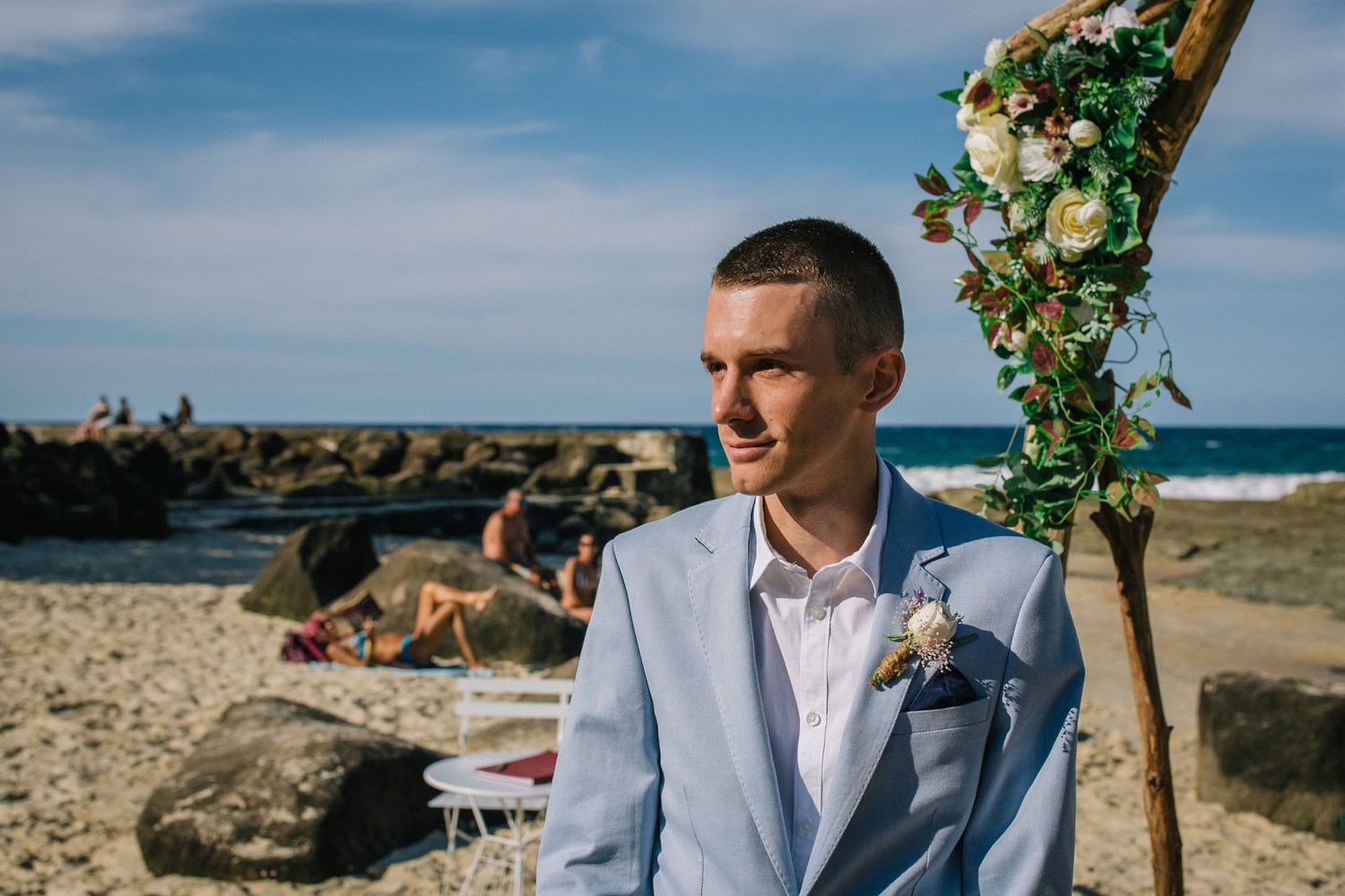 Beachside wedding ceremony with floral arch and ocean views.