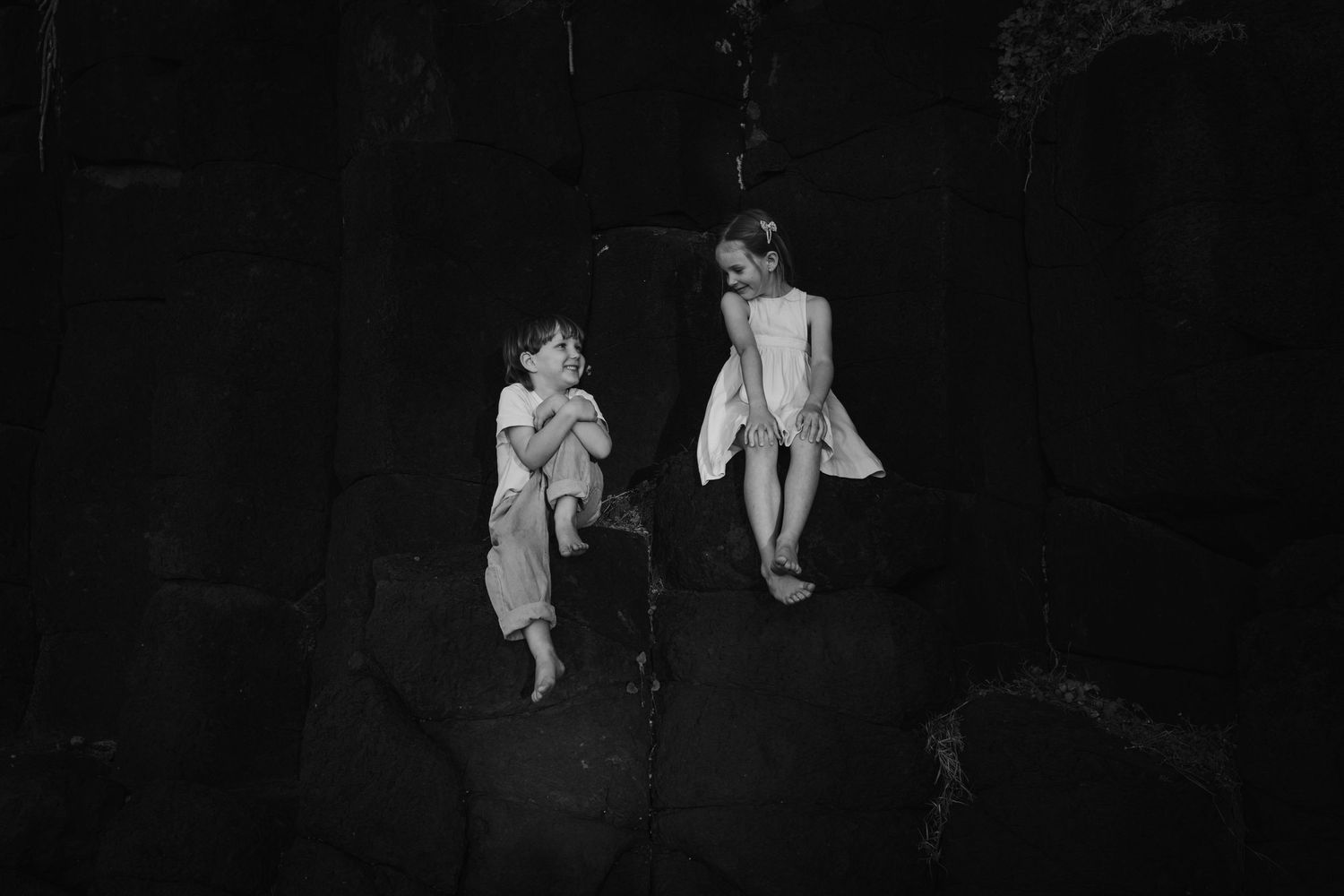 Dark moody scene with figures perched on coastal rocks.Fingal head family photos -  New South Wales