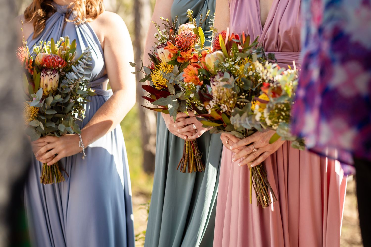 Wedding party members hold colorful fall bouquets with orange and yellow flowers.Gold Coast wedding photographer