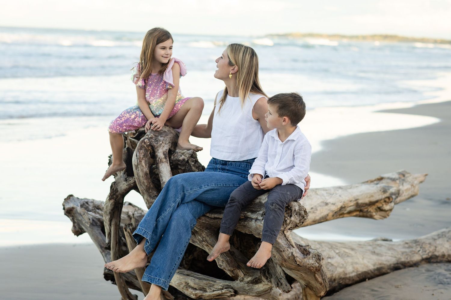 Family group sitting together on driftwood at the beach during golden hour.Family photography cabarita New South Wales Cabarita headland