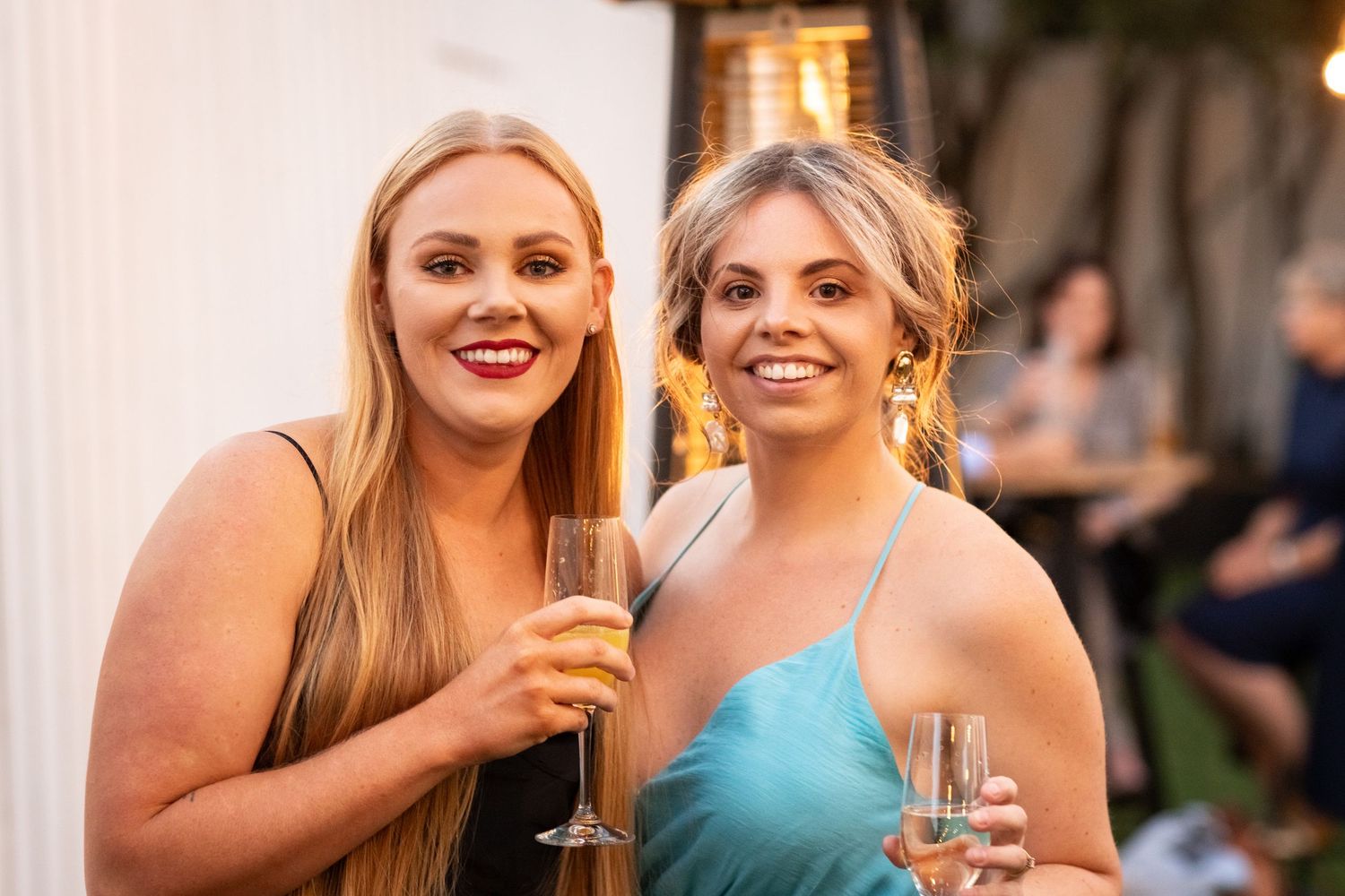 Wedding reception guests enjoying drinks and conversation at outdoor party.